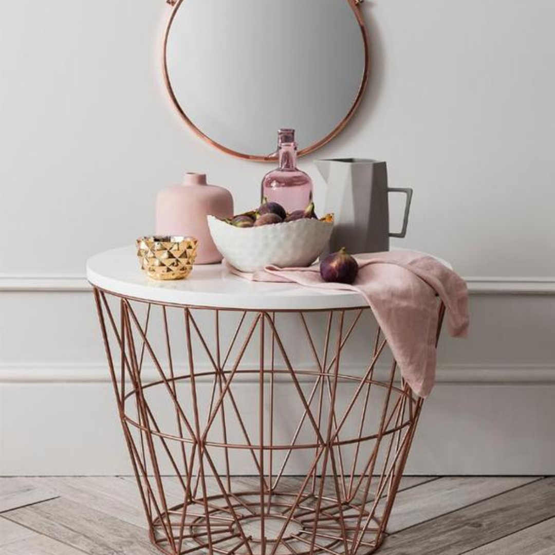 Cesto metalico decorativo con tapa blanca como peinador con un espejo rosado, la base del cesto es rose gold